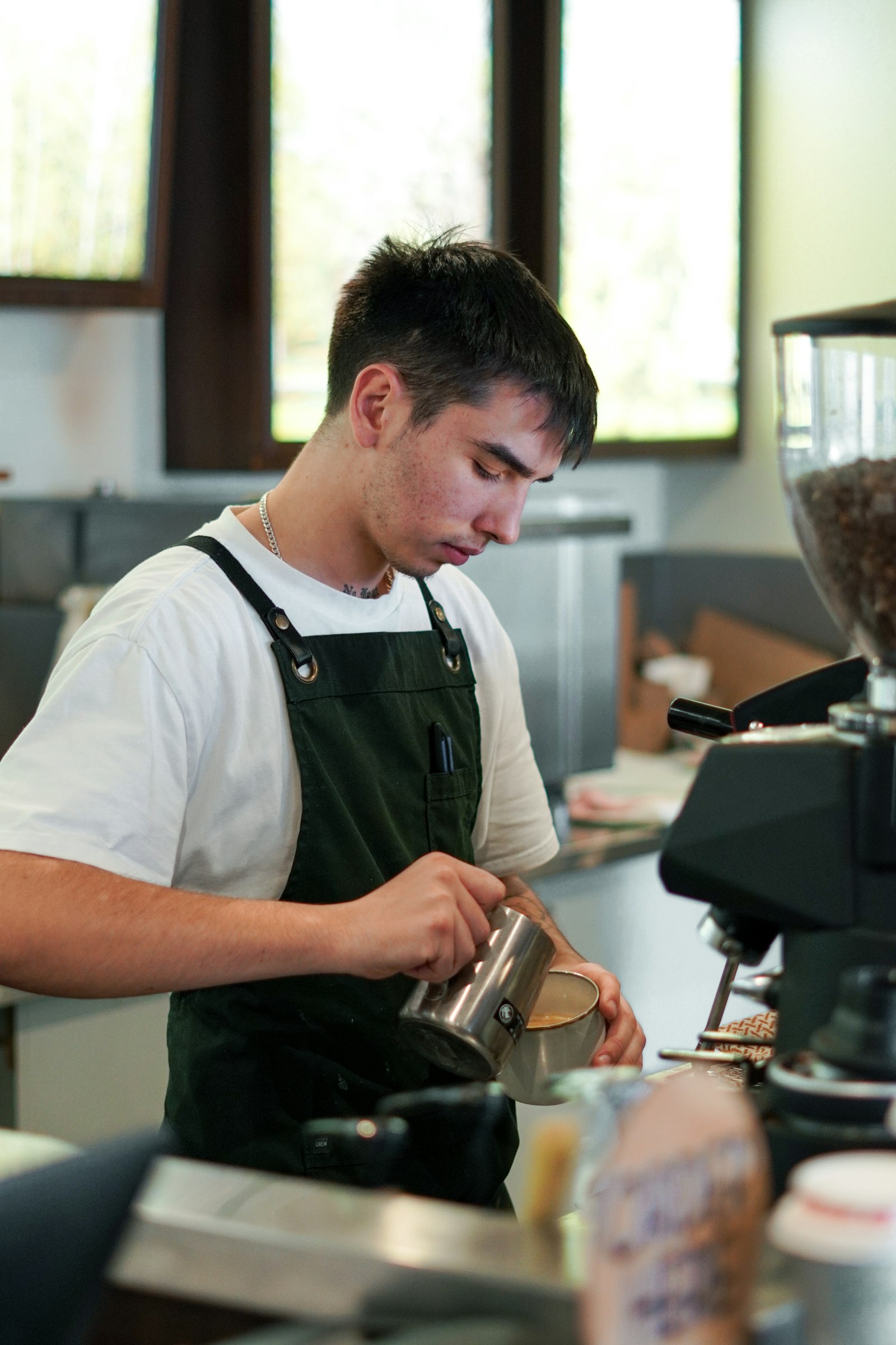 A young man in an apron preparing drinks in a cafe
